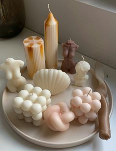 there are candles and seashells on the plate next to each other, along with shells