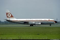 an airplane that is sitting on the runway in the grass and some trees behind it