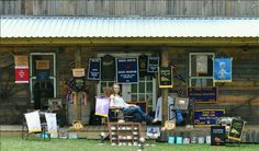 a woman sitting on a chair in front of a building with lots of signs hanging from it