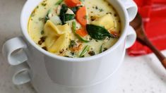 a white cup filled with soup on top of a table