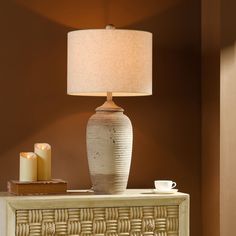 a table with a lamp on top of it next to a basket and candle holder