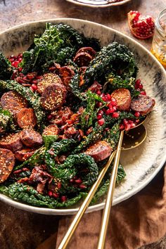 a white bowl filled with meat and greens on top of a table next to other foods