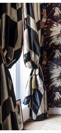 black and white curtains with gold tassels in front of a floral wallpaper