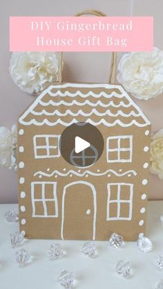 a gingerbread house gift bag is shown with flowers in the background and text overlay that reads diy gingerbread house gift bag