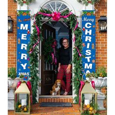 a woman standing in front of a christmas door with her dog on the doorstep and decorations around her