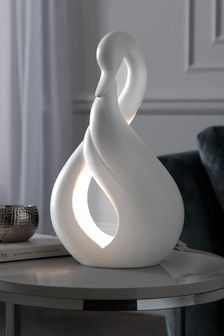 a white sculpture sitting on top of a table next to a book and glass vase