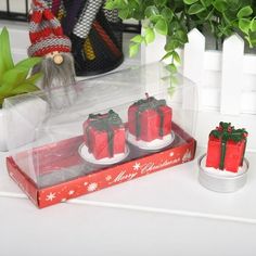 three small red presents sitting on top of a table next to a potted plant