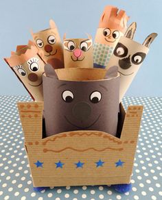 some paper animals in a cardboard box on a table with polka dot dots and blue background