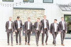 a group of men in suits standing next to each other on a cement ground near a building