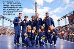 a group of people standing on top of a stage with medals in front of the eiffel tower