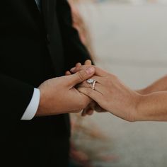 the bride and groom hold hands as they stand close to each other with their wedding rings on their fingers