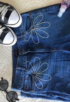 a pair of black shoes sitting on top of a blue jean skirt next to sunglasses