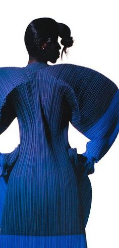 the back of a woman's blue dress with pleated sleeves and an intricate braid