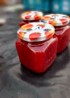 three jars with red liquid sitting on top of a table