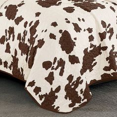 a brown and white cow print comforter on a bed