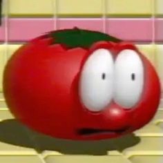 a cartoon tomato with eyes and nose sitting on the ground in front of a tiled wall