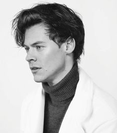 a man in a white coat and turtle neck sweater