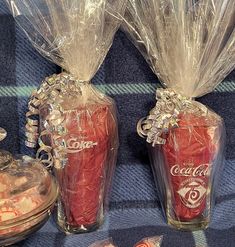 two glass vases filled with candy sitting on a tablecloth next to each other