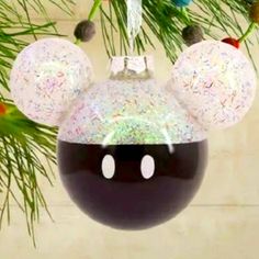 a mickey mouse ornament hanging from a christmas tree with sprinkles