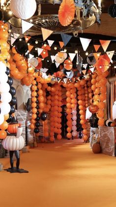 an orange, black and white party with balloons in the shape of pumpkins hanging from the ceiling