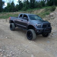 a gray truck driving down a dirt road