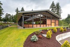 a large building sitting in the middle of a lush green field with lots of trees