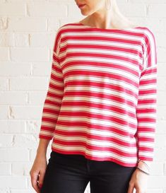 a woman standing in front of a brick wall wearing a red and white striped top