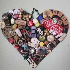 a heart - shaped decoration made out of various types of buttons and other items is hanging on the wall