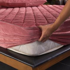 a person is pulling up the cover on a mattress that has been placed on top of it