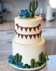 a three tiered cake decorated with succulents and bunting