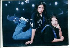 two young women sitting on the ground in front of a black background with white lights