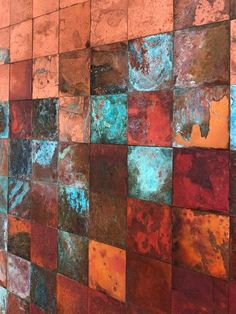 a wall made up of different colored tiles with rusted paint on the sides and bottom