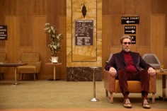 a man sitting in a chair next to a table with chairs and signs on it