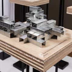 a model of a building on top of a wooden table with metal bars around it