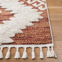 an area rug with tassels and fringe on the bottom is laying on a wooden floor