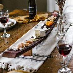 a wooden table topped with wine glasses and plates filled with food on top of it