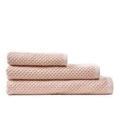 three towels folded on top of each other in light pink color, one with a white background