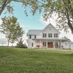 a large white house sitting on top of a lush green field