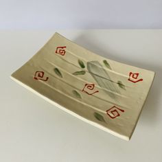 a decorative ceramic dish with red and green designs on it's edges, sitting on a white surface