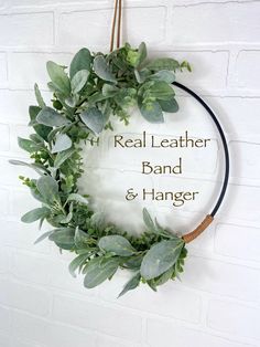 the real leather band and hanger is hanging on a brick wall with greenery