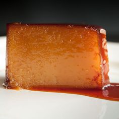 a piece of caramel cheesecake on a white plate with sauce drizzled around it