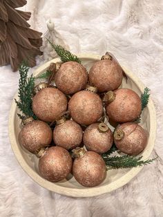 a bowl filled with lots of brown ornaments on top of a white blanket next to a plant