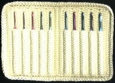 a crocheted white tray with six different colored needles in it and two rows of them