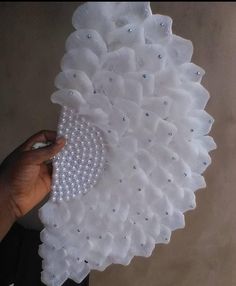 someone is holding a white doily with pearls on it