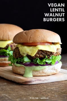 two burgers with cheese and lettuce on a cutting board