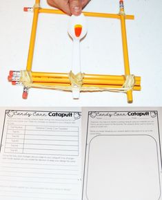 a hand holding a pencil over a paper with an orange and white object on it