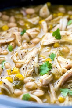 a bowl of chicken noodle soup with corn and cilantro