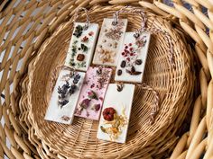 four small tags with flowers on them are sitting in a wicker basket next to other items