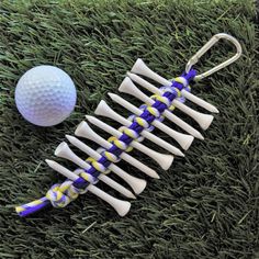 a golf ball and tees on the grass next to a bone shaped keychain