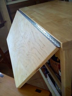 a wooden table with a metal strip on it's edge and drawers in the background